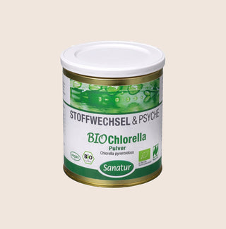 Canister of BIO Chlorella powder with green and white label on a beige background